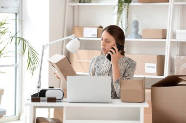 Ofiste cep telefonuyla konuşan paketli genç bir kadın.