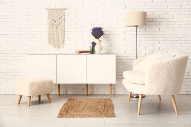 Aydınlık oturma odasının içinde çekmeceler, bank, kanepe, lamba ve güzel lavanta çiçekleri