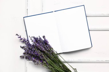 Güzel lavanta çiçekleri ve açık ahşap zemin üzerine boş bir kitap.