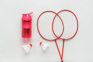 Badminton raketleri, mekik horozları ve arka planda bir şişe su.