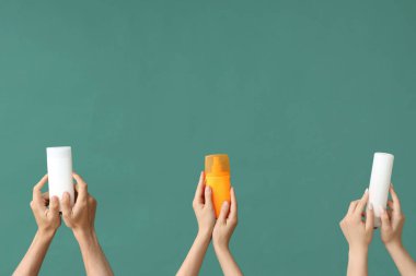 Yeşil arka planda güneş kremi şişeleri olan kadın elleri
