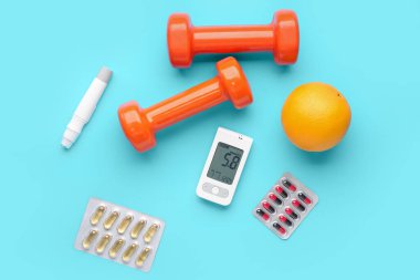 Haplı glukometre, turuncu, keçeli kalem ve mavi arka planda dambıl. Diyabet kavramı