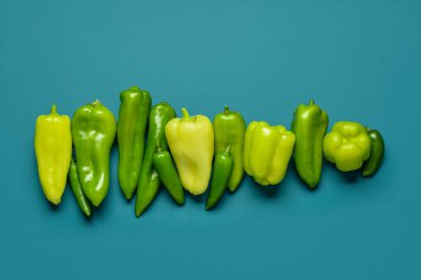 Mavi arka planda farklı taze biberler.