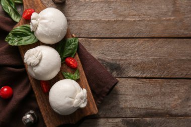 Tahta arka planda fesleğenli ve domatesli lezzetli Burrata peyniri.