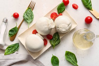 Lezzetli Burrata peyniri, fesleğenli ve domatesli beyaz masa.