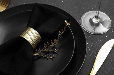 Siyah tabaklar, peçete ve altın yapraklarla kaplanmış, yakın plan.