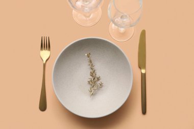 Bej masa üzerinde altın yapraklar ve çatal bıçak takımı olan zarif bir masa.