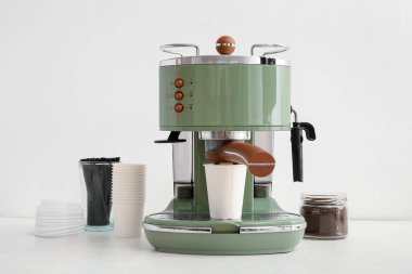 Beyaz arka planda kahve bardakları, kapakları, pipetleri ve pudrası olan modern kahve makinesi.