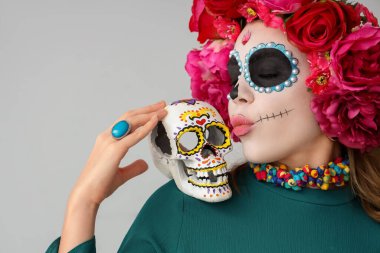 Kafatası boyalı genç bir kadın arka planda öpüşüyor, yakın plan. Meksika Ölüler Günü (El Dia de Muertos) kutlamaları