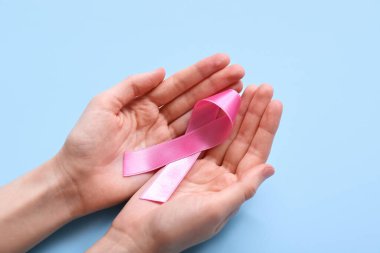 Mavi arka planda pembe kurdeleli bir kadın. Göğüs kanseri farkındalığı konsepti