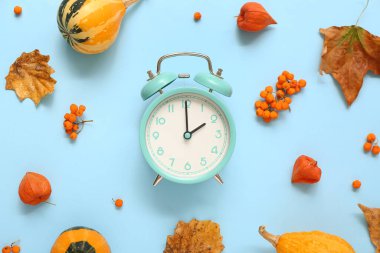 Çalar saat, düşmüş yapraklar ve mavi arka planda böğürtlenler