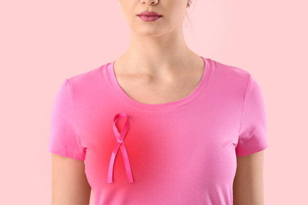 Молодая женщина с розовой лентой на цветном фоне. Концепция информированности о раке груди