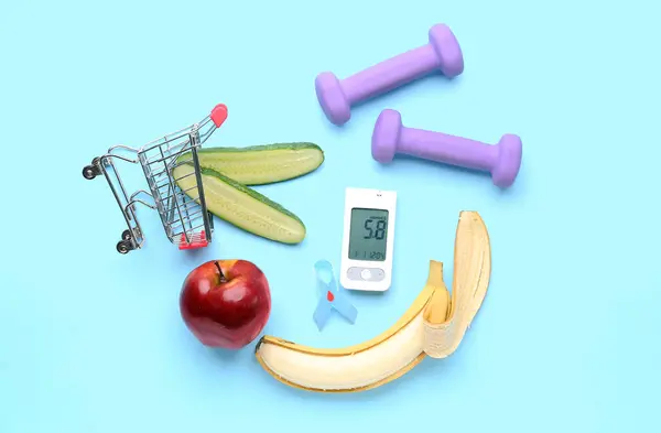 stock image Glucometer with shopping cart, food, dumbbells and awareness ribbon on blue background. Diabetes concept