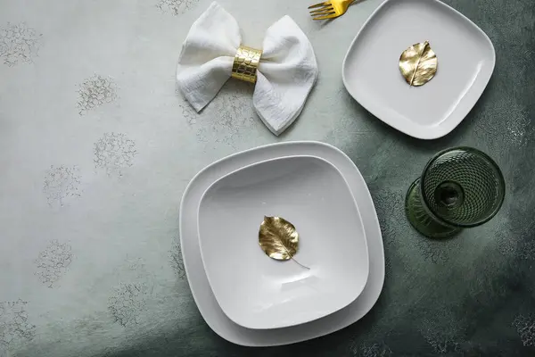 Elegant table setting with golden leaves on grey table