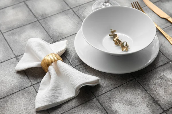 Elegant table setting with golden leaves on grey tiled background