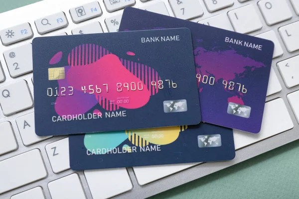 Credit cards with computer keyboard on green background, closeup. Online shopping