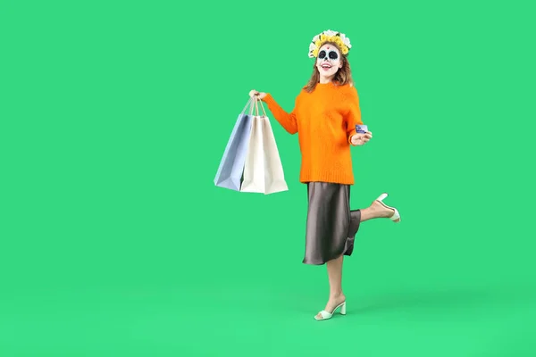 Junge Frau Mit Bemaltem Totenkopf Kreditkarte Und Einkaufstaschen Auf Grünem — Stockfoto