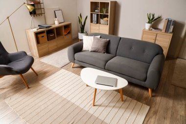 Masada dizüstü bilgisayarı ve kanepesi olan modern oturma odasının içinde.