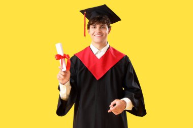 Sarı arka planda diploması olan erkek öğrenci.