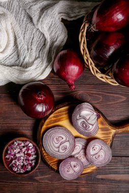 Tahta ve hasır kasede taze kesilmiş kırmızı soğanlar ahşap arka planda.