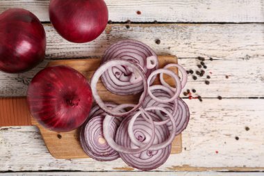 Beyaz ahşap zemin üzerinde taze soğan ve biber dilimleri olan tahta.