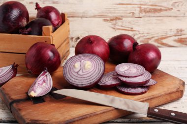 Beyaz ahşap arka planda taze kesilmiş kırmızı soğan ve kutu.