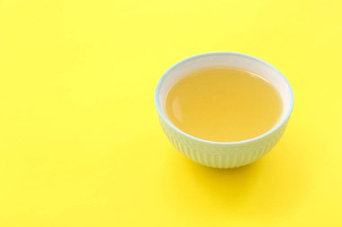 Sarı arka planda bir kase lezzetli sebze suyu.