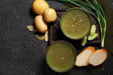 Siyah arka planda bir kase lezzetli sebze suyu.