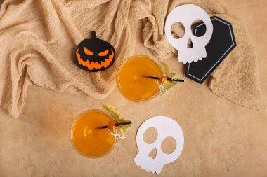 Cadılar Bayramı için bir bardak lezzetli turuncu kokteyl ve bej arka planda kağıt dekor.