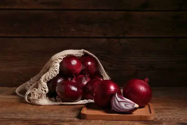 Brett Und Saitentasche Mit Frischen Roten Zwiebeln Auf Holzgrund — Stockfoto