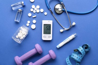 Mavi arka planda glukometre, mızrak, ilaç ve dambıl kompozisyonu. Diyabet kavramı