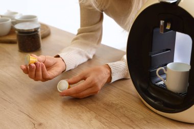 Mutfakta kremalı ve modern kahve makineli olgun bir kadın, yakın plan.