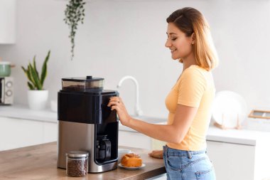 Genç bayan mutfakta kahve yapıyor.