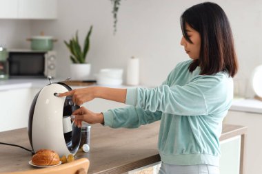Güzel Asyalı kadın mutfakta kahve yapıyor.