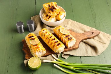 Yeşil ahşap arka planda limonlu ızgara mısır koçanı.