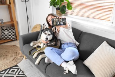 İri köpekli mutlu genç kadın evde selfie çekiyor.