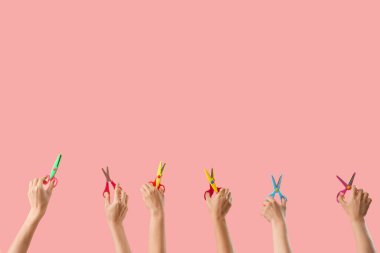 Pembe arka planda kağıt makaslı bir sürü el