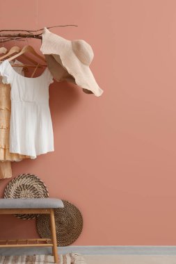 Salondaki pembe duvarın yanındaki bankta ve asılı elbiselerle.