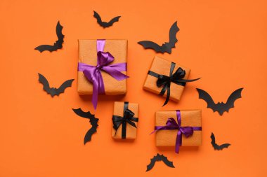 Cadılar Bayramı kutlaması için hediye kutuları ve kağıt yarasalarla birlikte renk arkaplanı üzerine kompozisyon