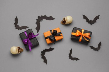 Gri arkaplanda hediye kutuları ve Cadılar Bayramı süslemeleri olan kompozisyon