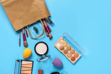 Mavi arka planda makyaj malzemesi olan alışveriş torbası.
