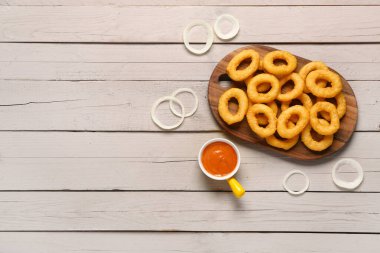 Kızarmış soğan halkaları ve gri ahşap arka planda sos.