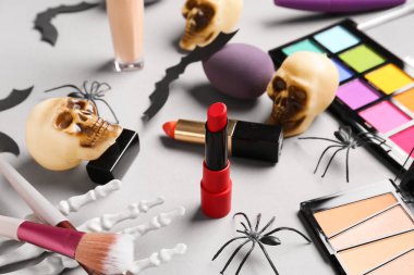 Farklı dekoratif kozmetik ürünleri ve gri arka planda Cadılar Bayramı dekorasyonu