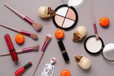 Farklı dekoratif kozmetik ürünleri ve gri arka planda Cadılar Bayramı dekorasyonu