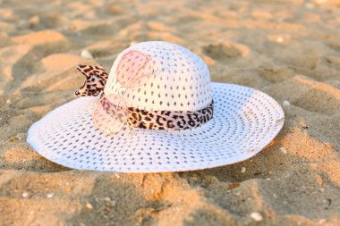 Pembe güneş gözlüğü ve kumdaki şapka.