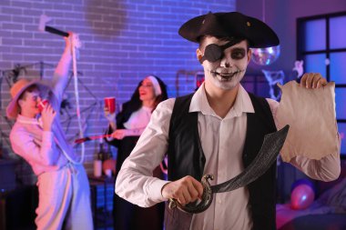 Cadılar Bayramı partisinde elinde kılıç ve haritayla korsan gibi giyinmiş genç bir adam.