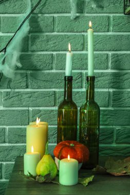 Cadılar Bayramı balkabaklarıyla yanan mumlar ve karanlık odada düşen yapraklar.