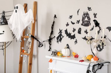 Balkabaklı şömine rafı, dökülen yapraklar, mumlar ve Cadılar Bayramı dekoru oturma odasında.