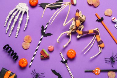 Farklı Cadılar Bayramı süslemeleri ve mor arka planda tatlı şekerlemeleri olan kompozisyon