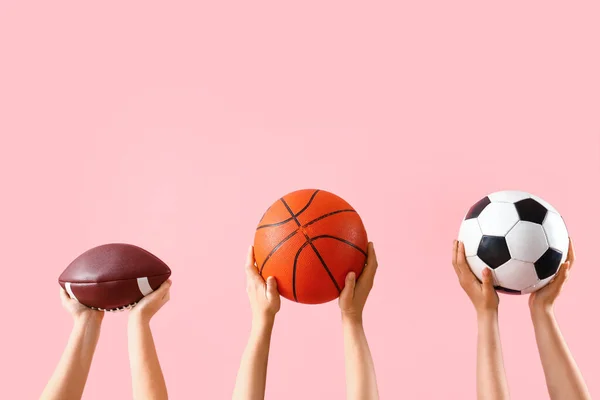 Manos Femeninas Sosteniendo Diferentes Bolas Deportivas Sobre Fondo Rosa —  Fotos de Stock